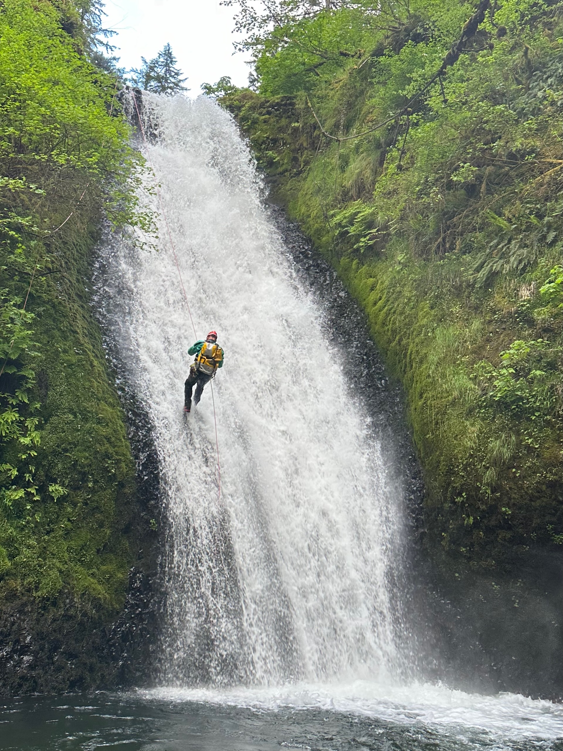 someone doing free-hanging rappel down a waterfall